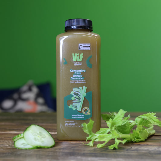 Bottle of Vif cucumber juice with slices and leaves on a wooden surface against a green background